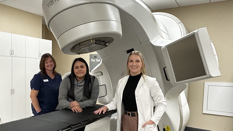 Dr. Trageser and MedVet caregivers standing beside a linear accelerator used for veterinary radiation therapy.